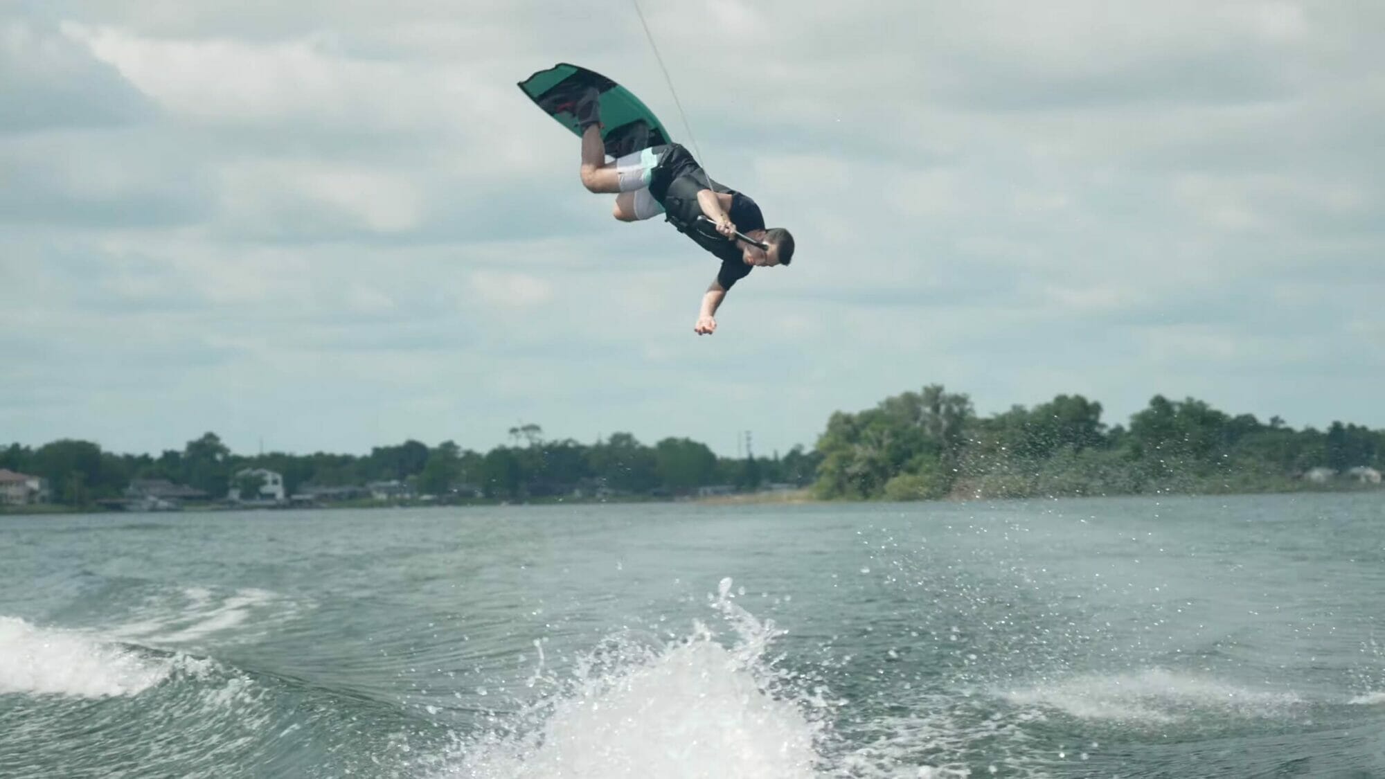 A man wakeboarding in the air over a body of water.