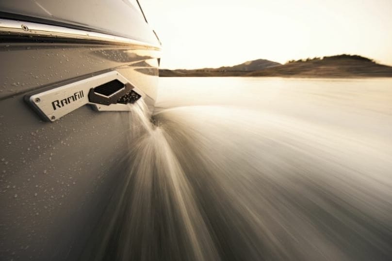 The door of a wakesurf boat with water coming out of it.