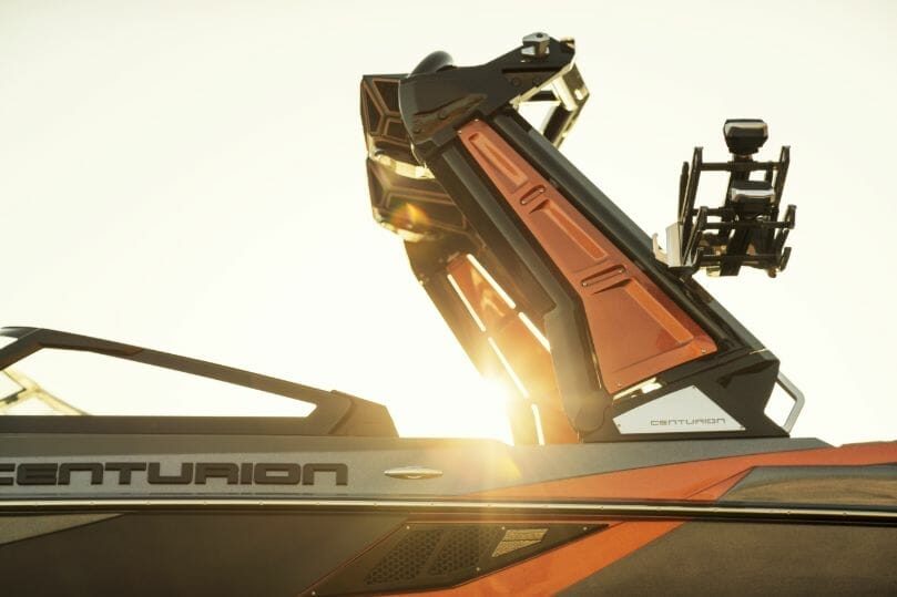 A black and orange wakesurf boat with a camera attached to it.