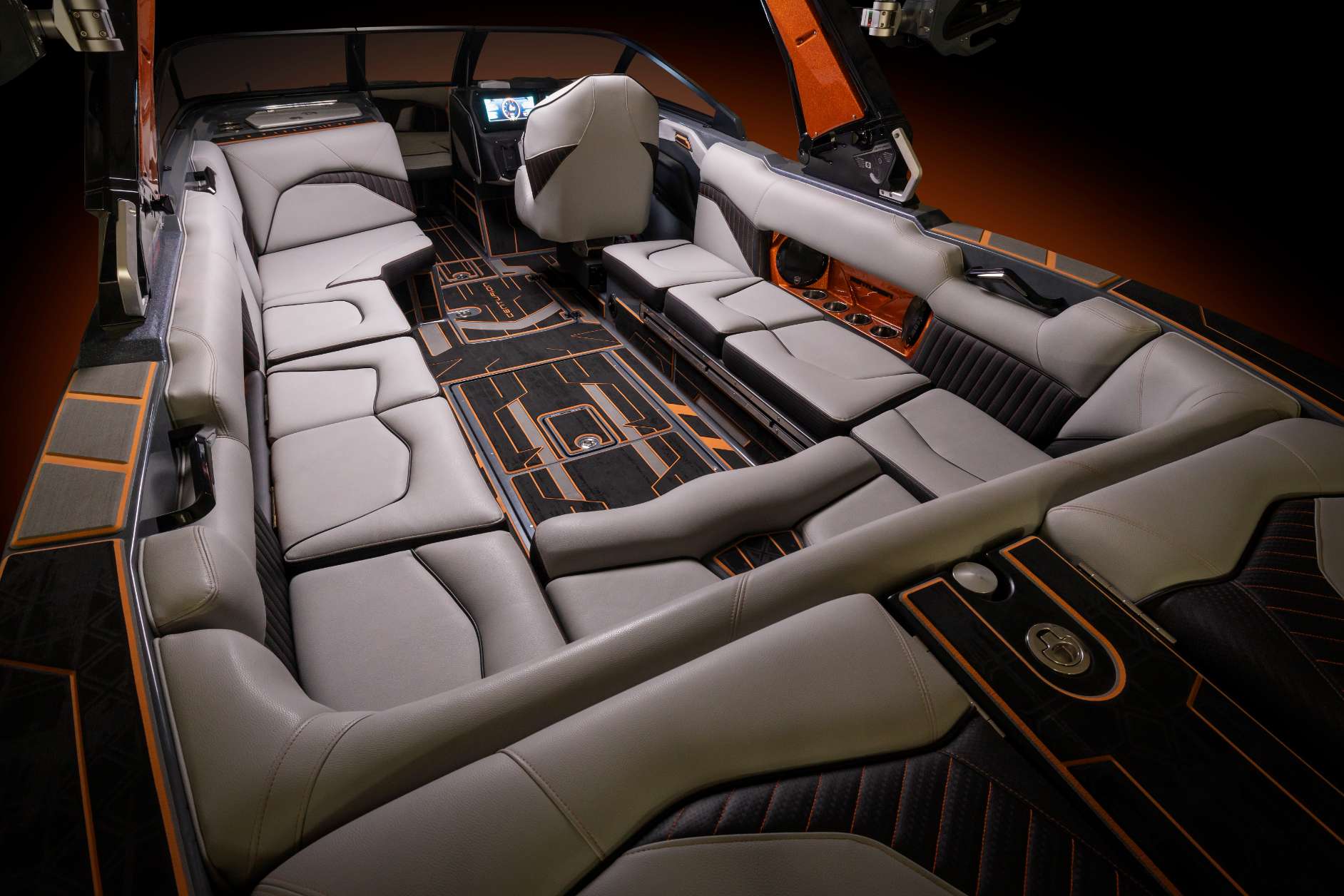The interior of a wakesurf boat with black and orange seats.