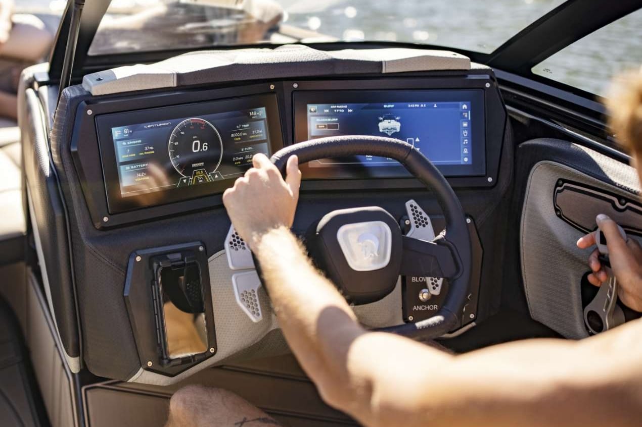 A man is driving a wakesurf boat with a touchscreen dashboard.