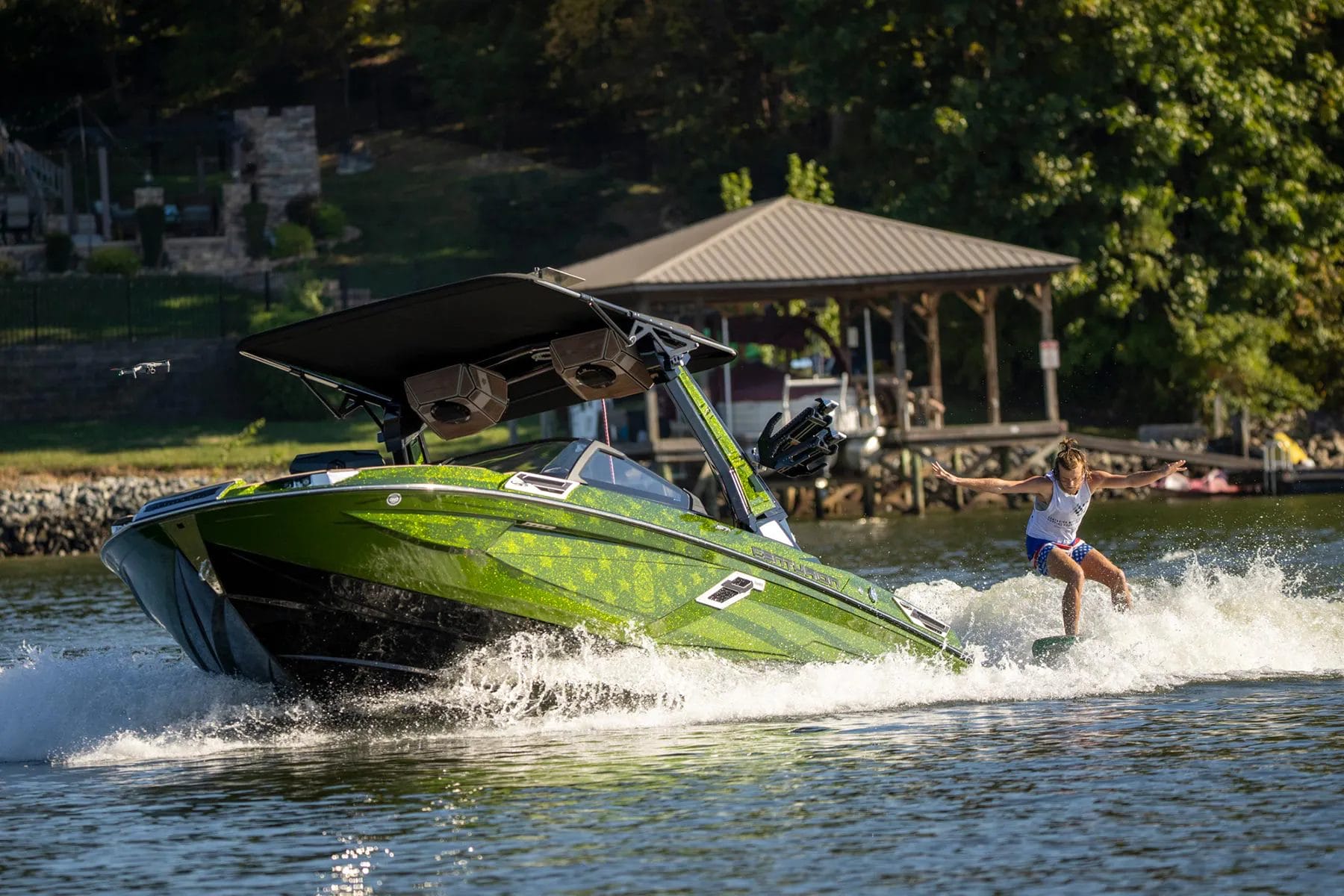 A woman is riding a wakesurf board on a green boat.