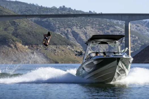 A man is jumping off a wakesurf boat into the water.