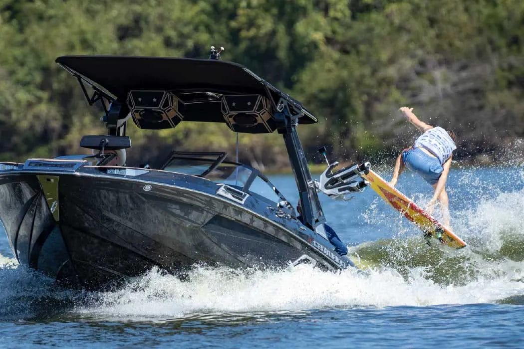 A man riding a wakeboard on a wakesurf boat.