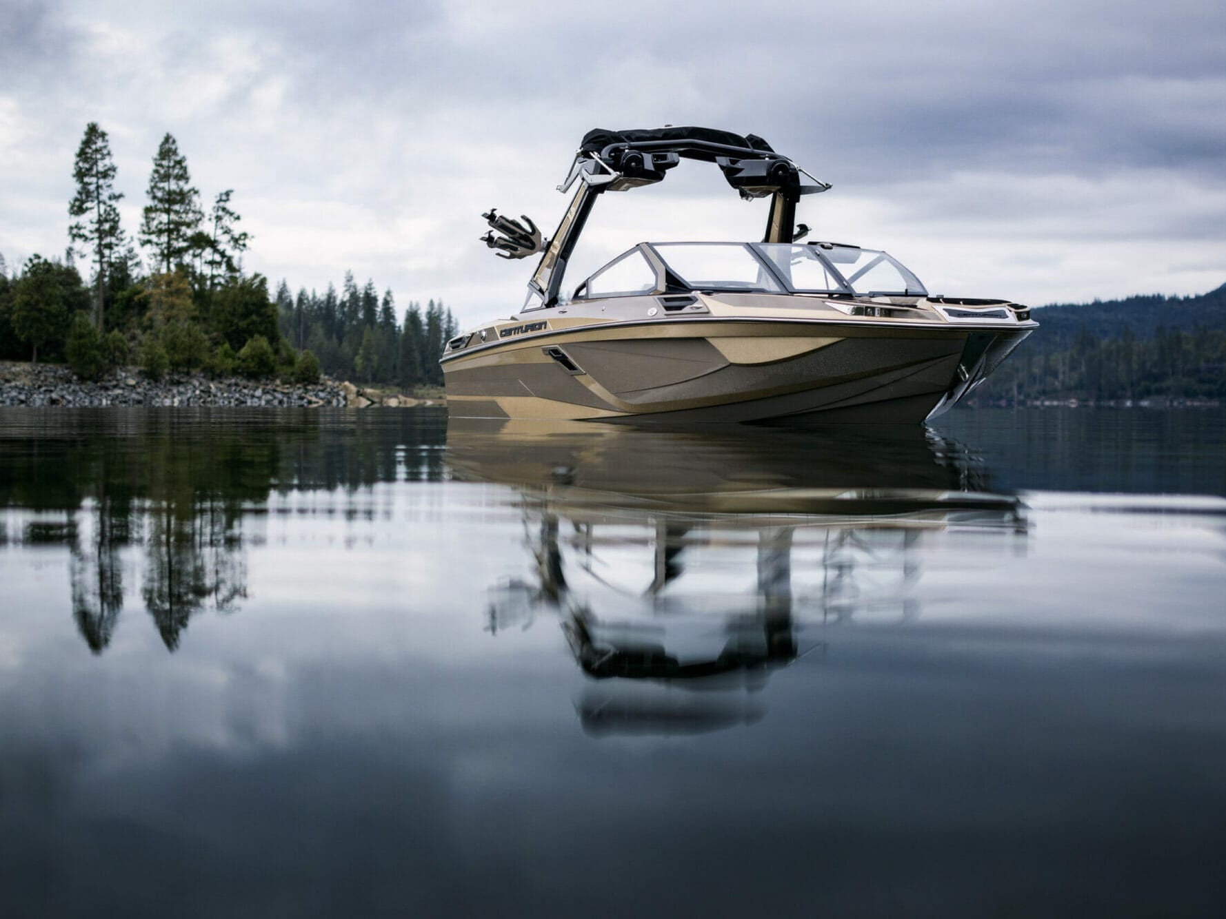 A wakesurf boat is floating on a lake.