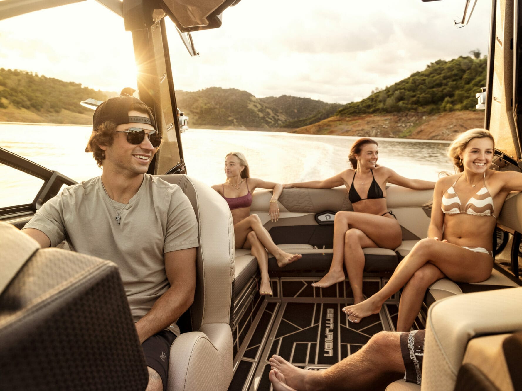A group of people sitting in the back of a wakeboat.