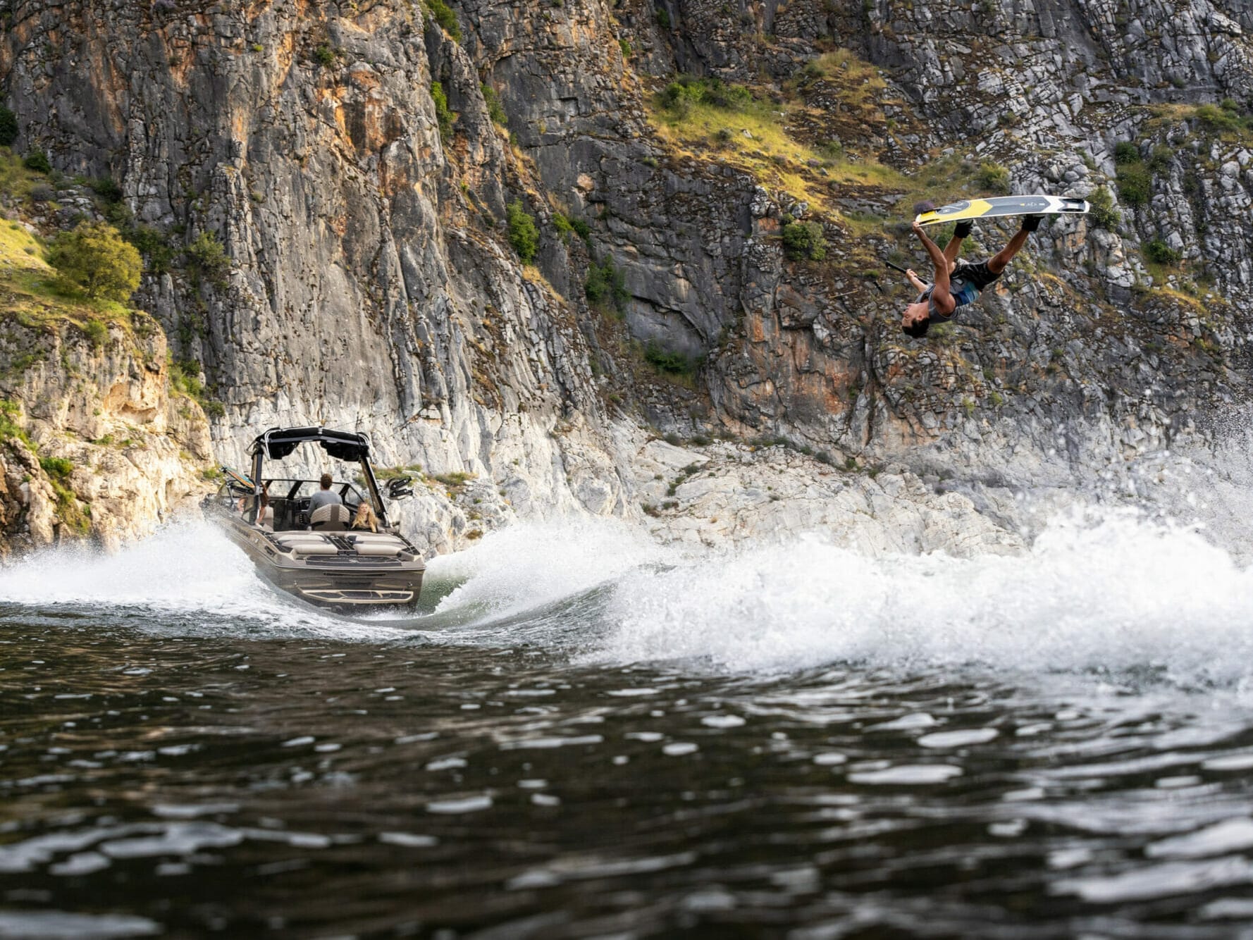 A man is riding a wakeboard over a wakeboat.