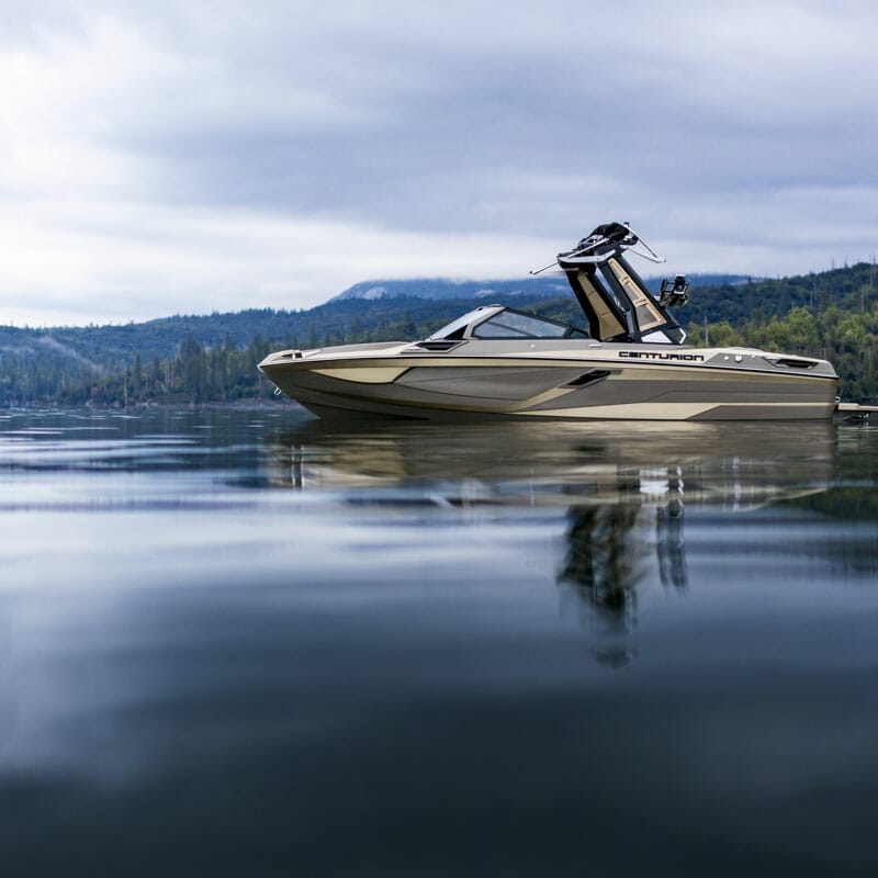 A wakesurf boat is floating on a lake.