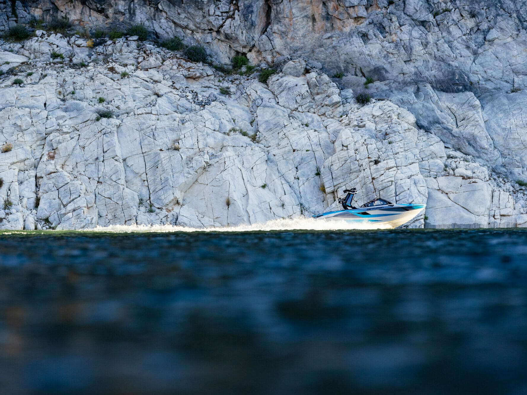 A person is riding a jet ski near a rocky cliff.