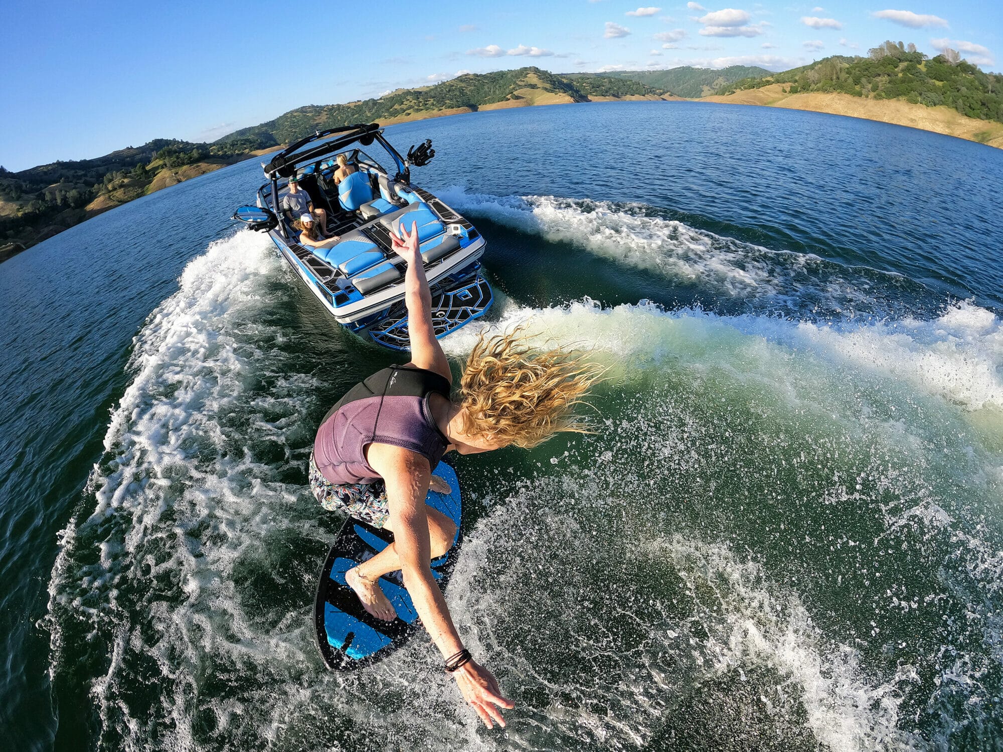 A woman riding a wakesurf board on a lake.