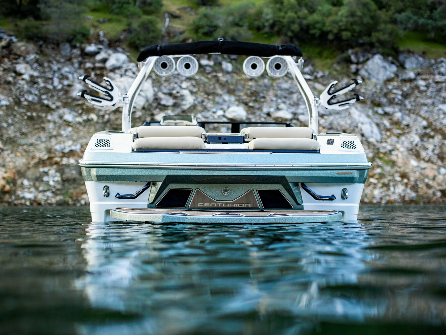 A white wakesurf boat is floating in a body of water.