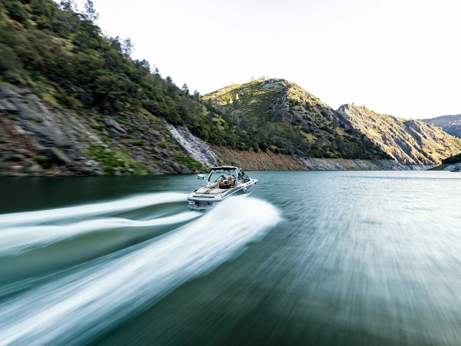 A wakeboat speeding down a river.