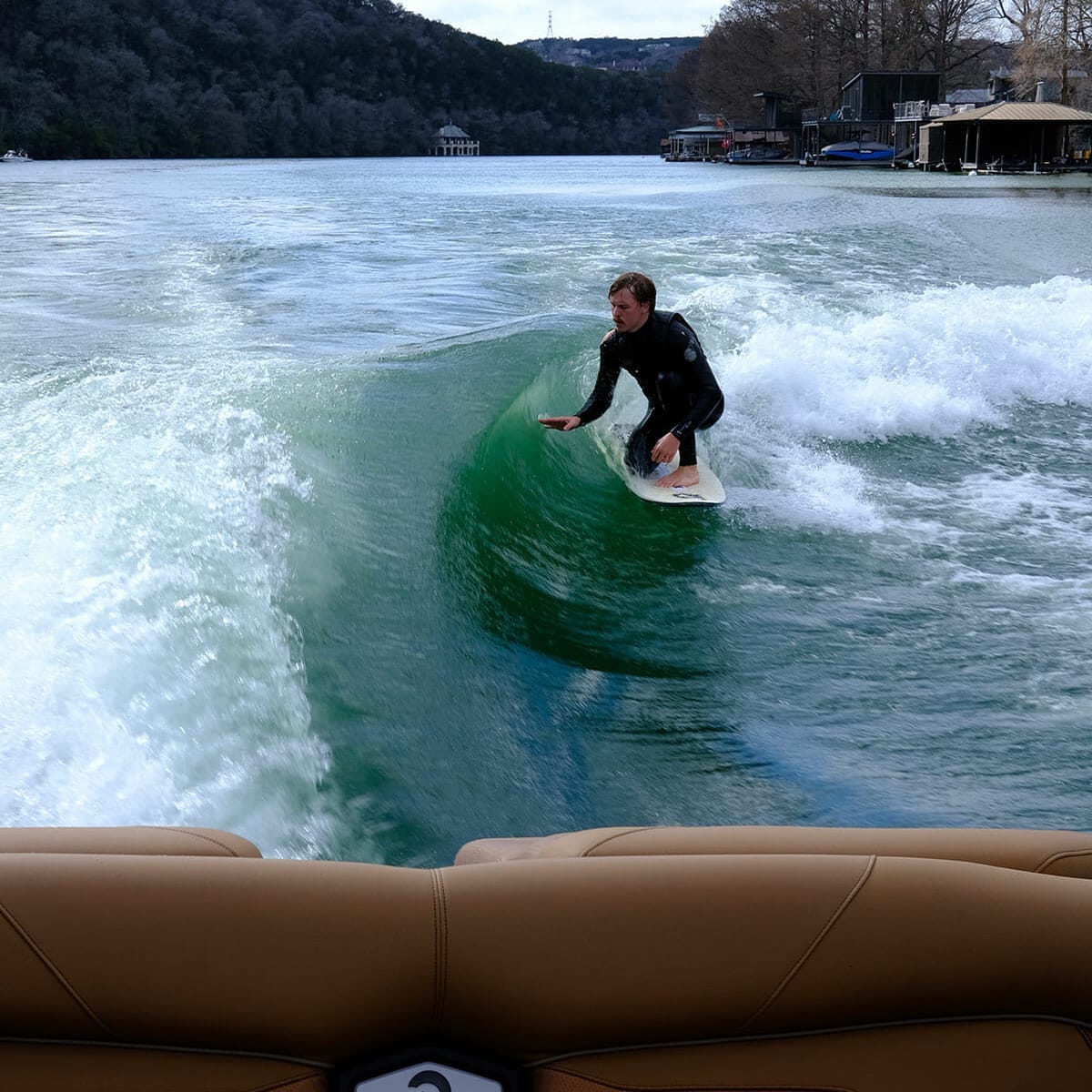 A man riding a wakesurf board in a wakeboat.