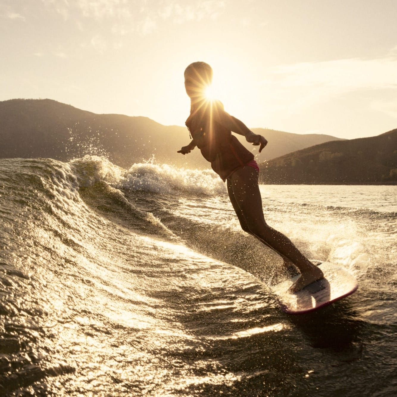 Kenzie Hickey, a woman, effortlessly rides a wave on her surfboard.