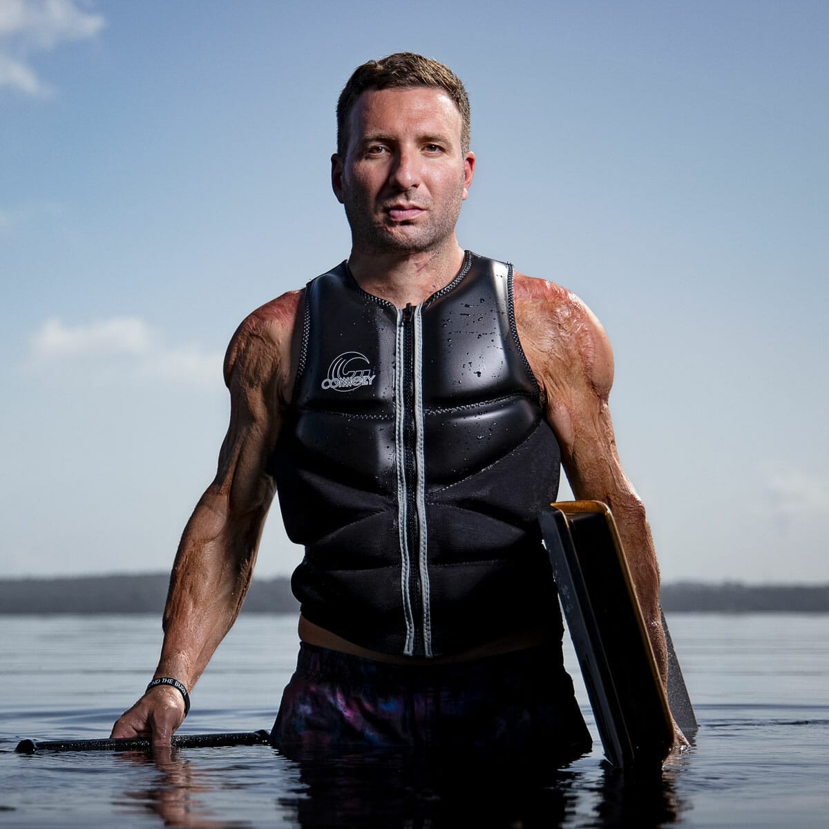 A man in a wetsuit wakesurfing on a wakesurf board.