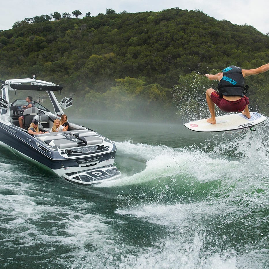 A man wakesurfing behind a wakeboat.
