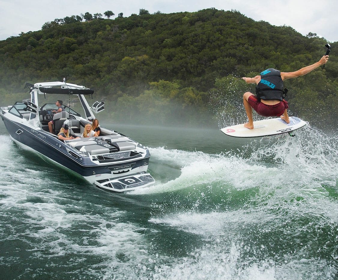 A man wakesurfing behind a wakeboat.