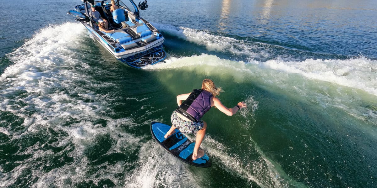 A man is wakesurfing on a wakeboard.