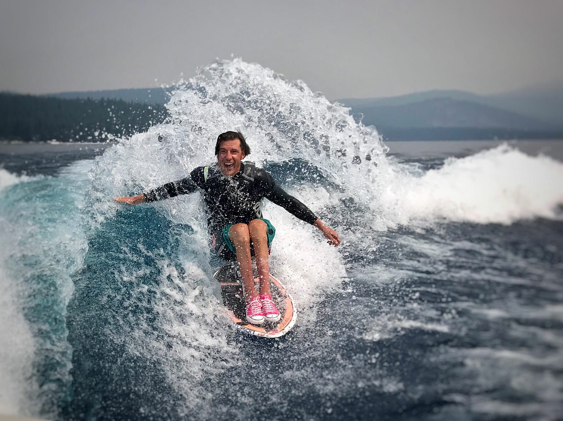 A person riding a wave on a wakesurf board.