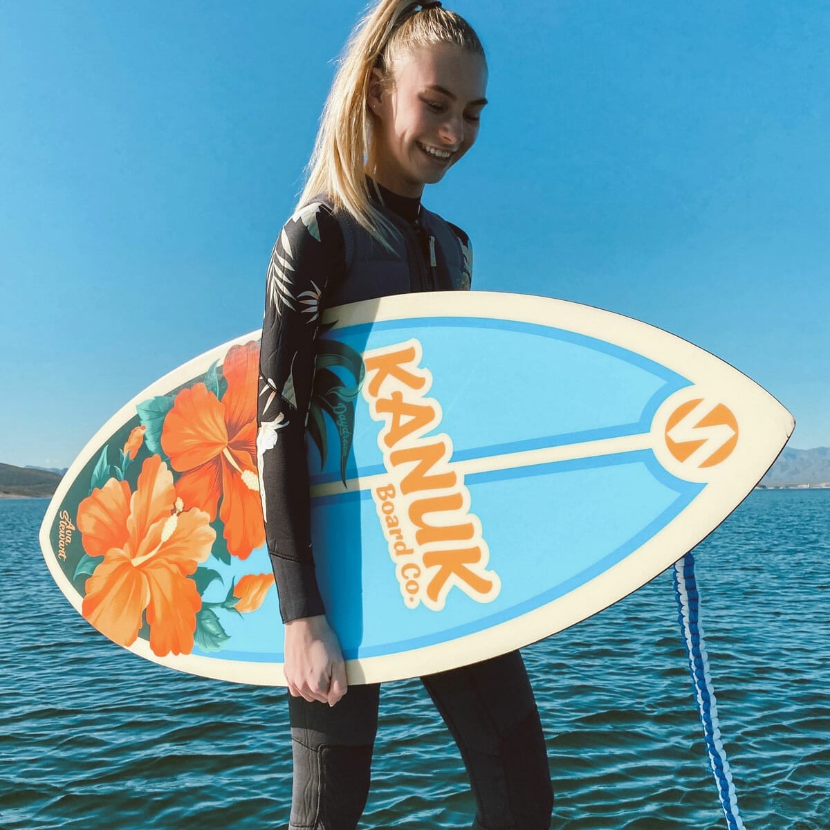 A woman standing on a wakesurf board.