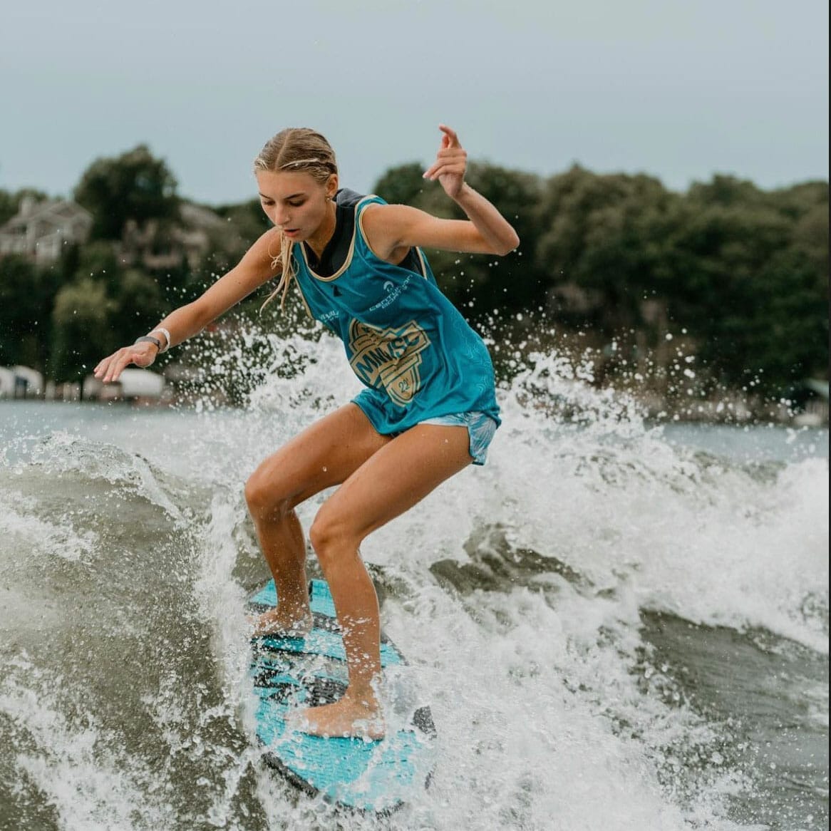 A girl riding a wave on a wakesurf board.