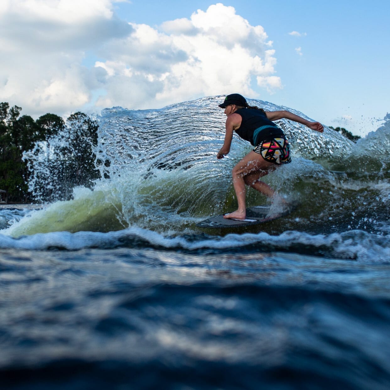 A person riding a wave on a wakesurf board.