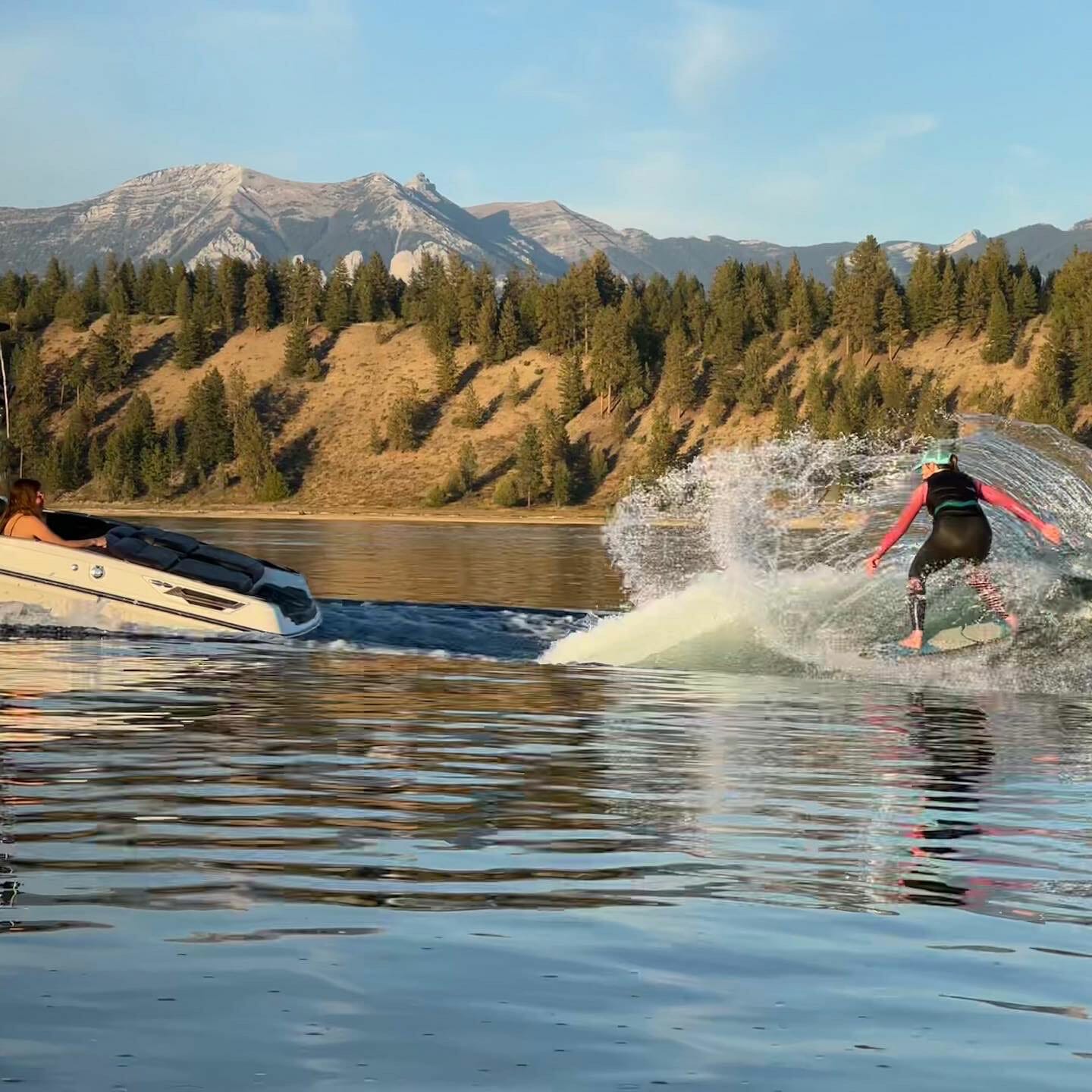A person is wakesurfing near a wakeboat.