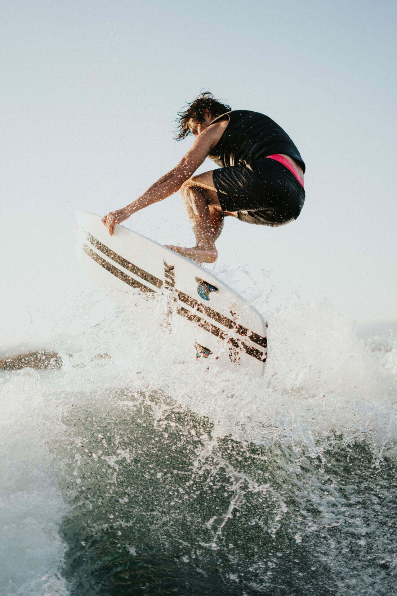 A man wakesurfing behind a boat on a wave.