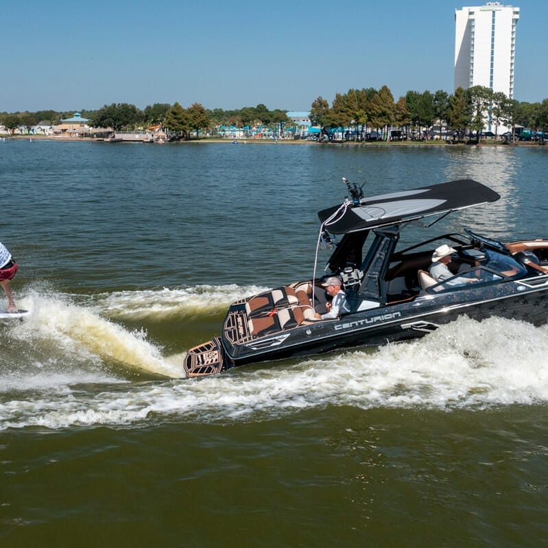 A man is riding a wakesurf boat on the water.