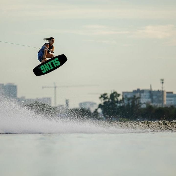 A person wakesurfing behind a boat on a lake.