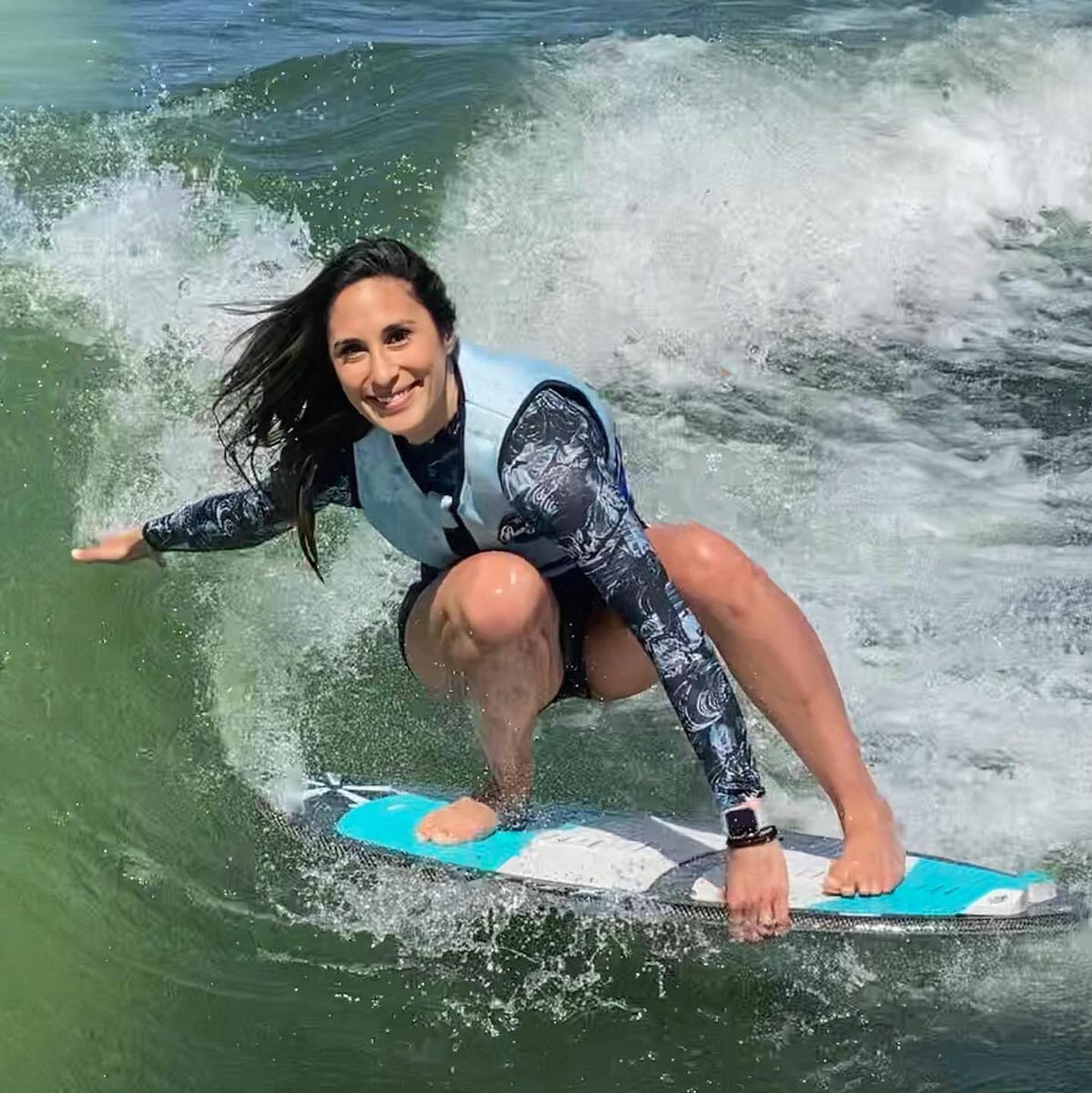 A woman wakesurfing on a surfboard.
