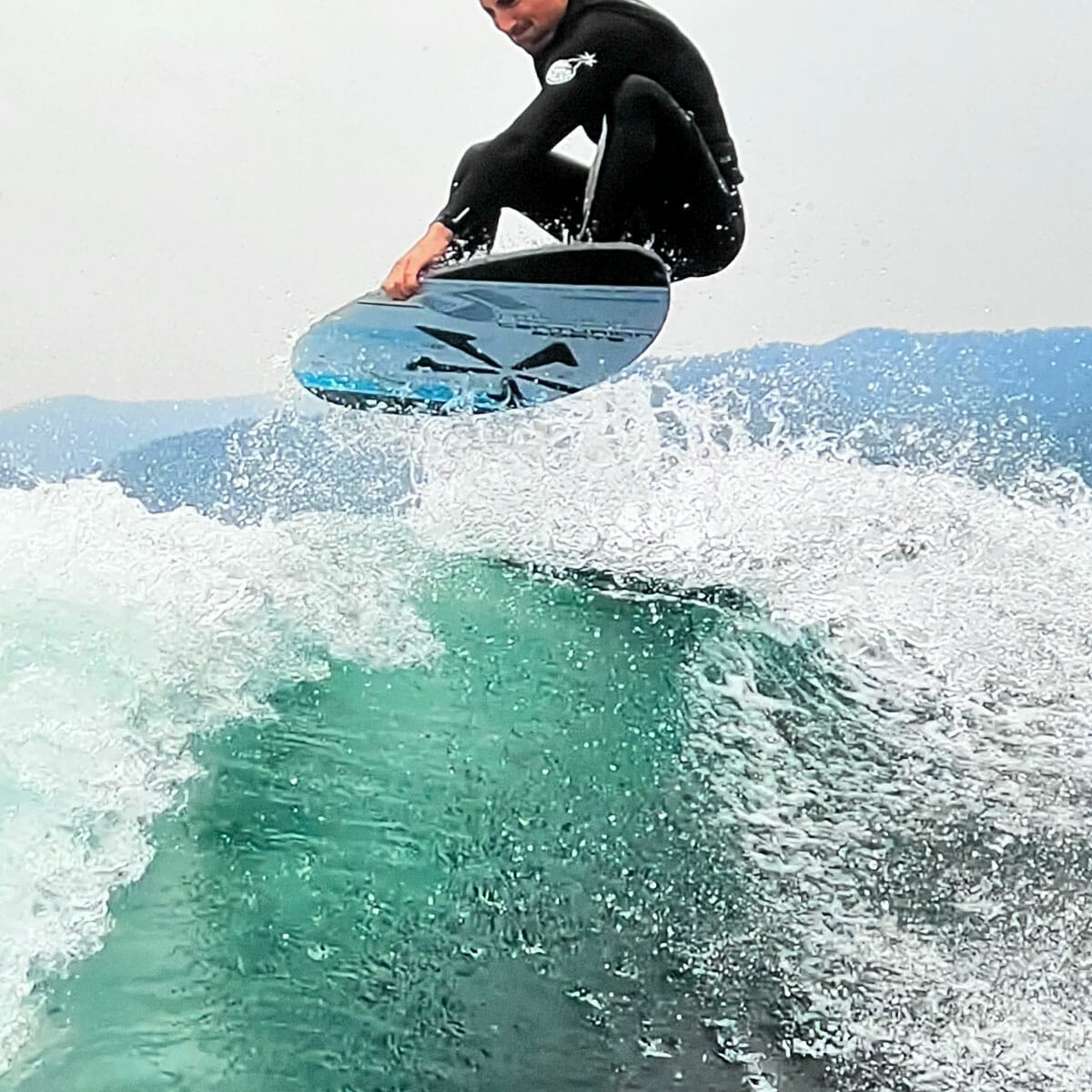 A man riding a wave on a surfboard in a wet suit.