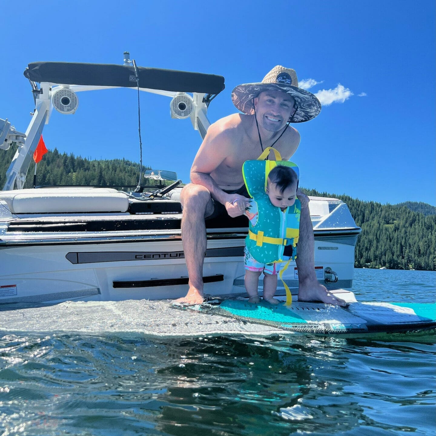 A man and a baby on a wakesurf board in the water.