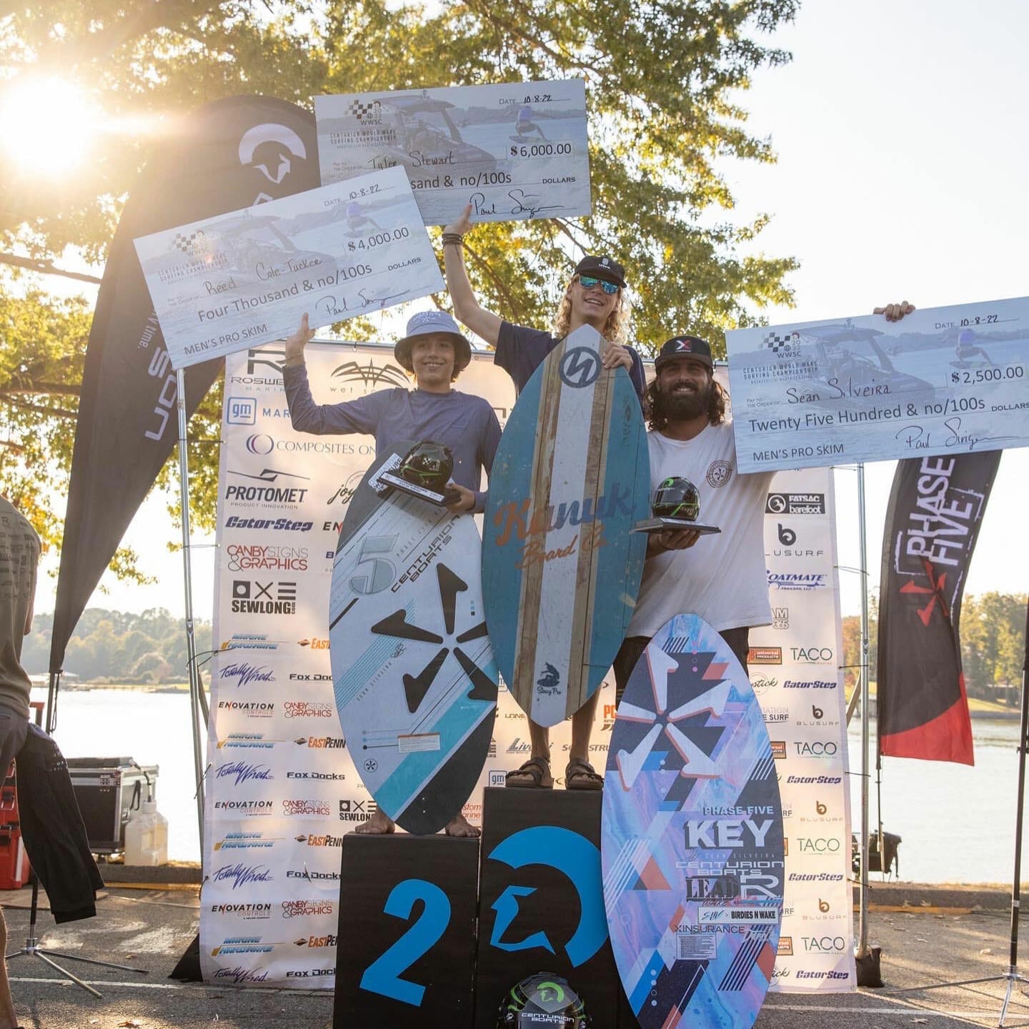 A group of people standing on top of a podium with surfboards and wakesurf boards.