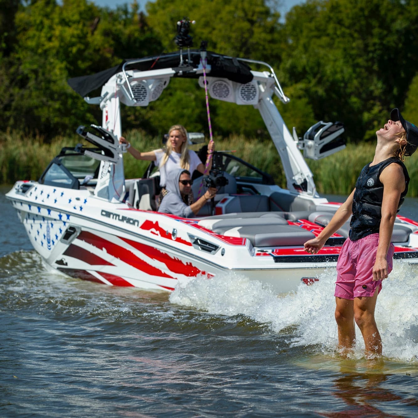 Two people standing on a wakesurf boat.