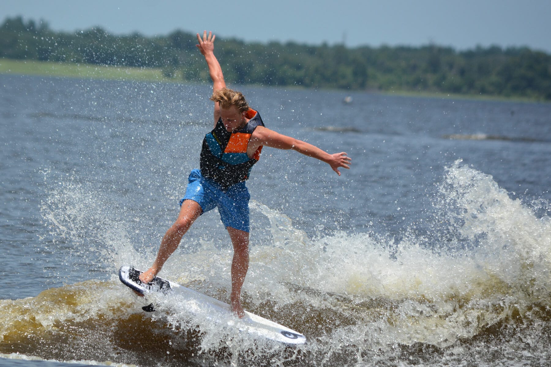 A man riding a wave on a wakesurf board.