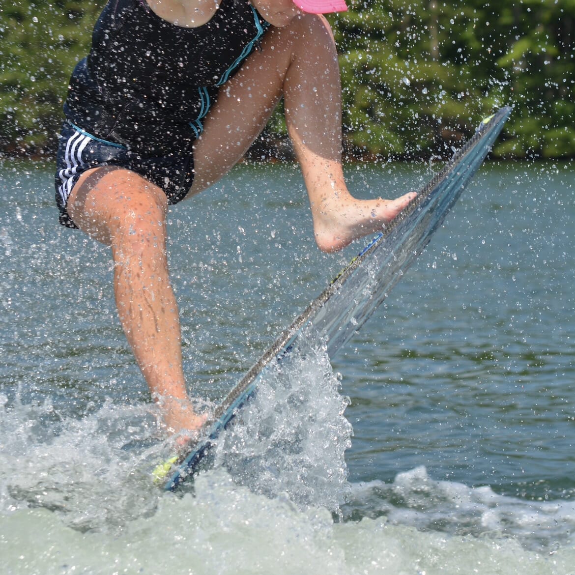 A woman is riding a wave on a wakesurf board.