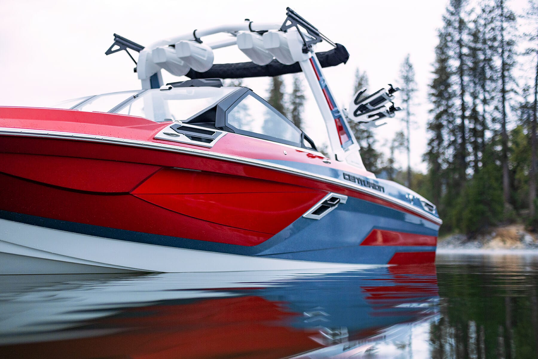 A red and blue wakeboat is sitting on a body of water.