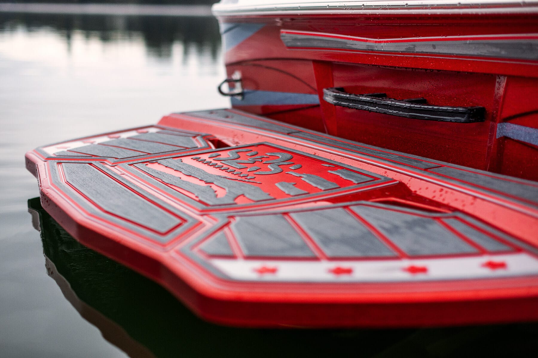 A red wakesurf boat with a red seat on it.