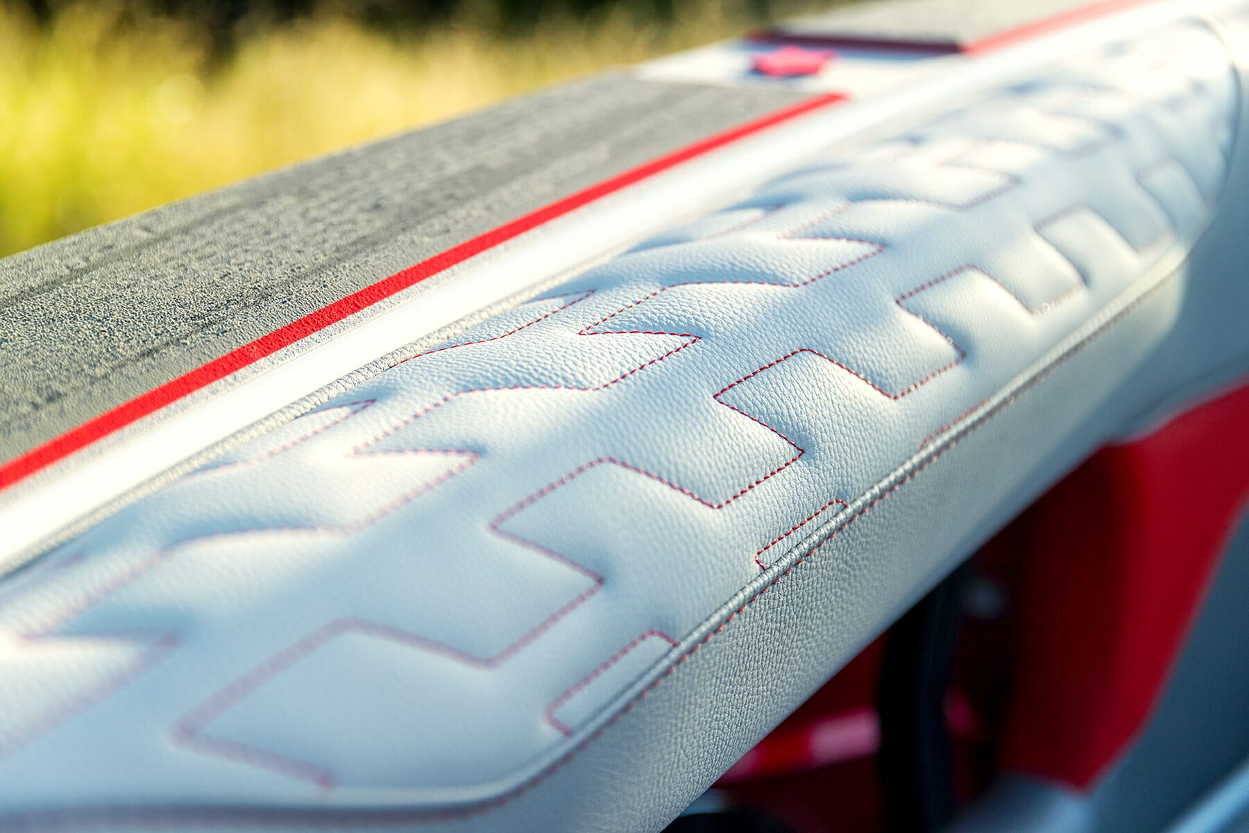 A close up of a wakesurf board seat with red and white stitching.