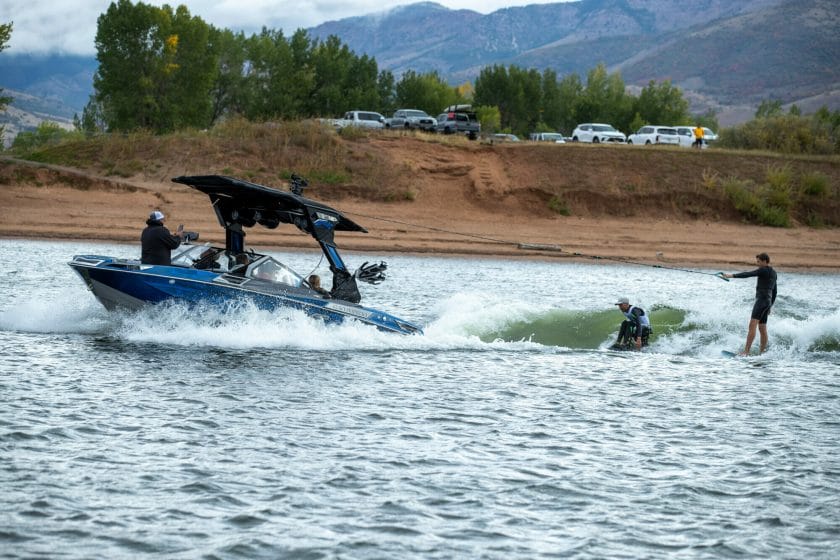 A group of people riding a wakeboat in the water.
