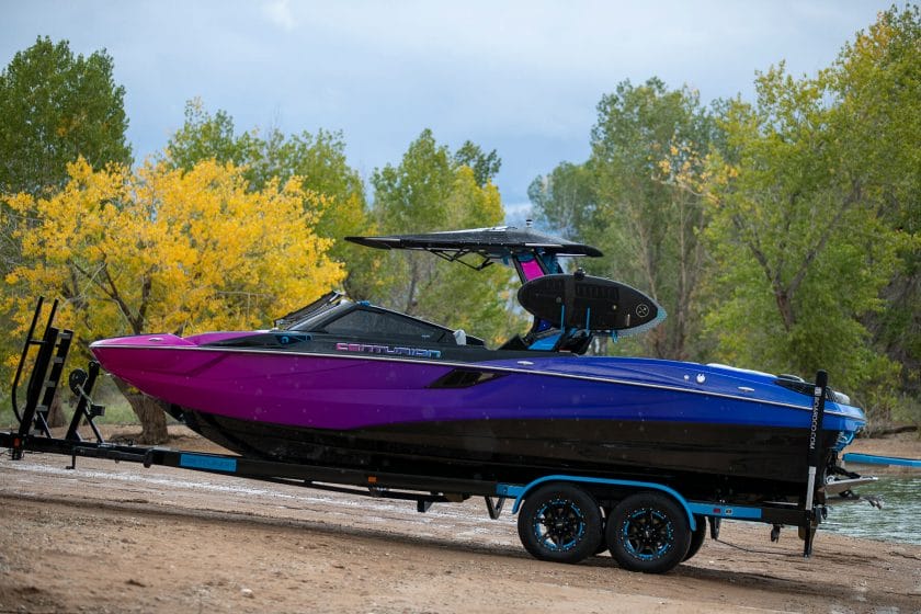 A blue and purple wake boat parked on a trailer.