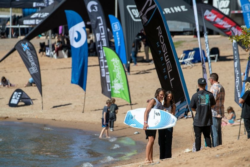 2024 WWSC Day 2 Recap: Group of people with surfboards on a beach.