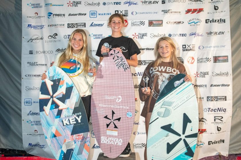 Three girls posing for a photo with surfboards at the 2024 WWSC Day 2 Recap.