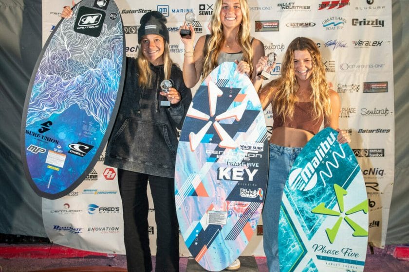 Three women showcasing their surfboards on Day 2 of the 2024 World Women's Surfing Championship.