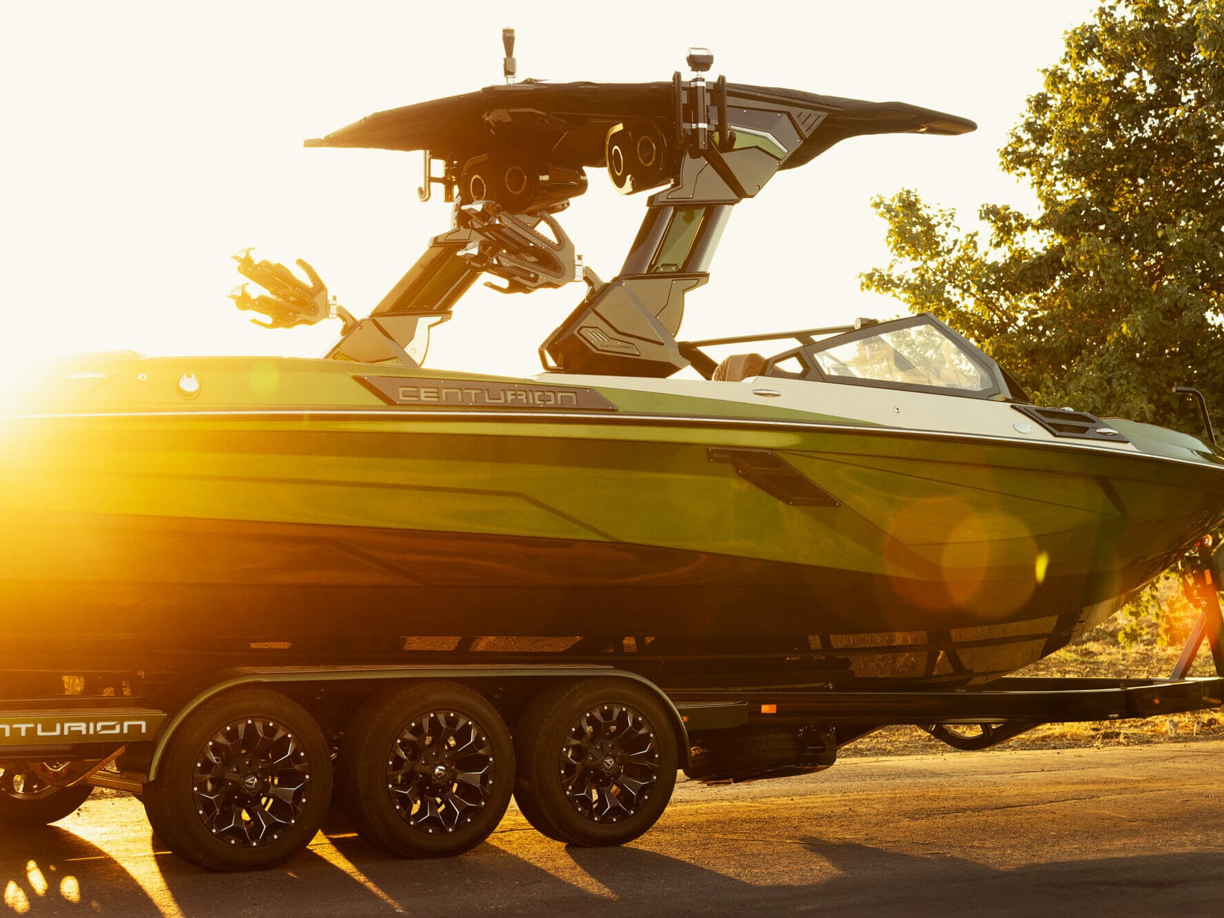 A green and black wakesurf boat on a trailer.