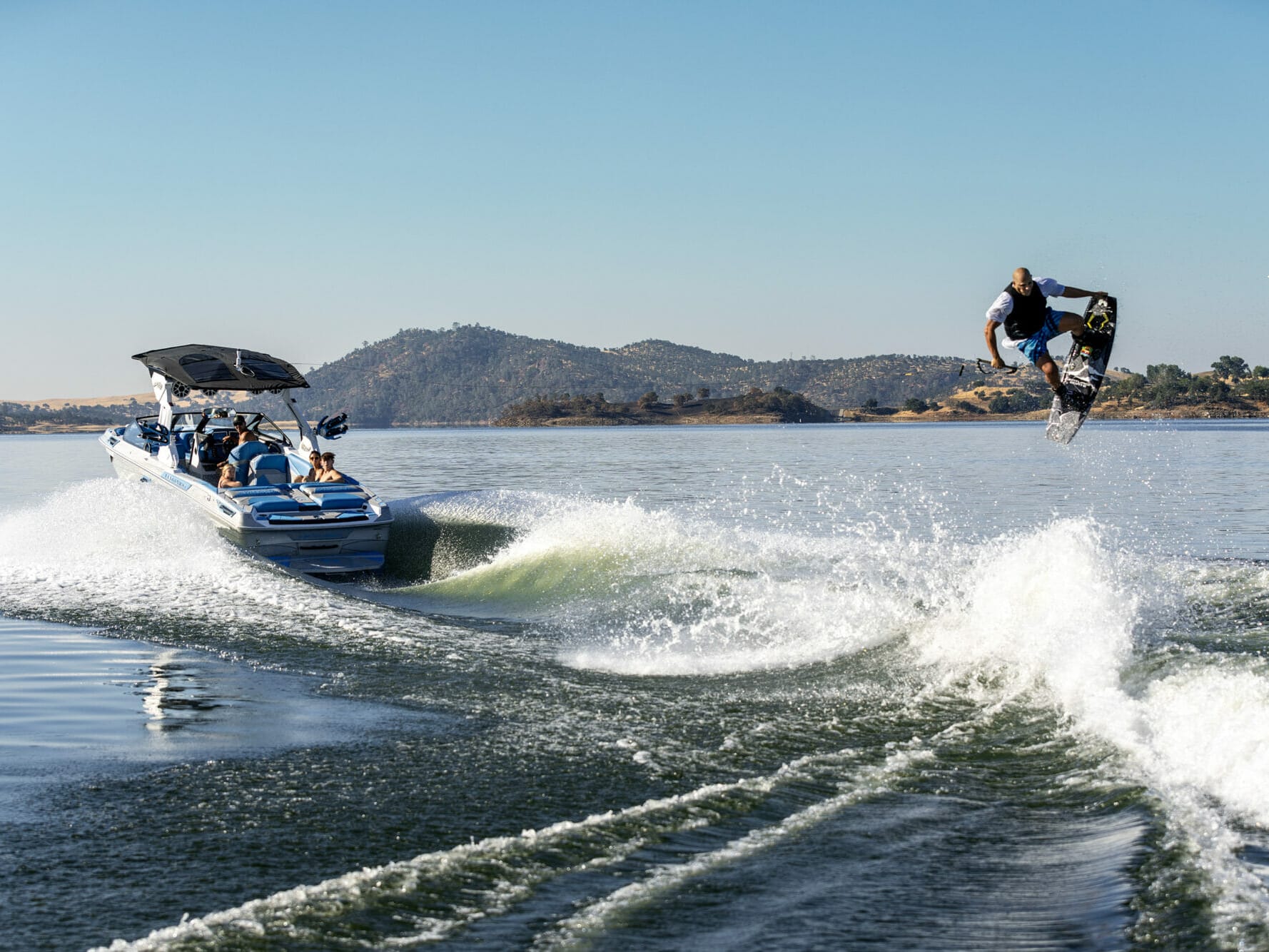 A man is riding a wakesurf board on a boat.