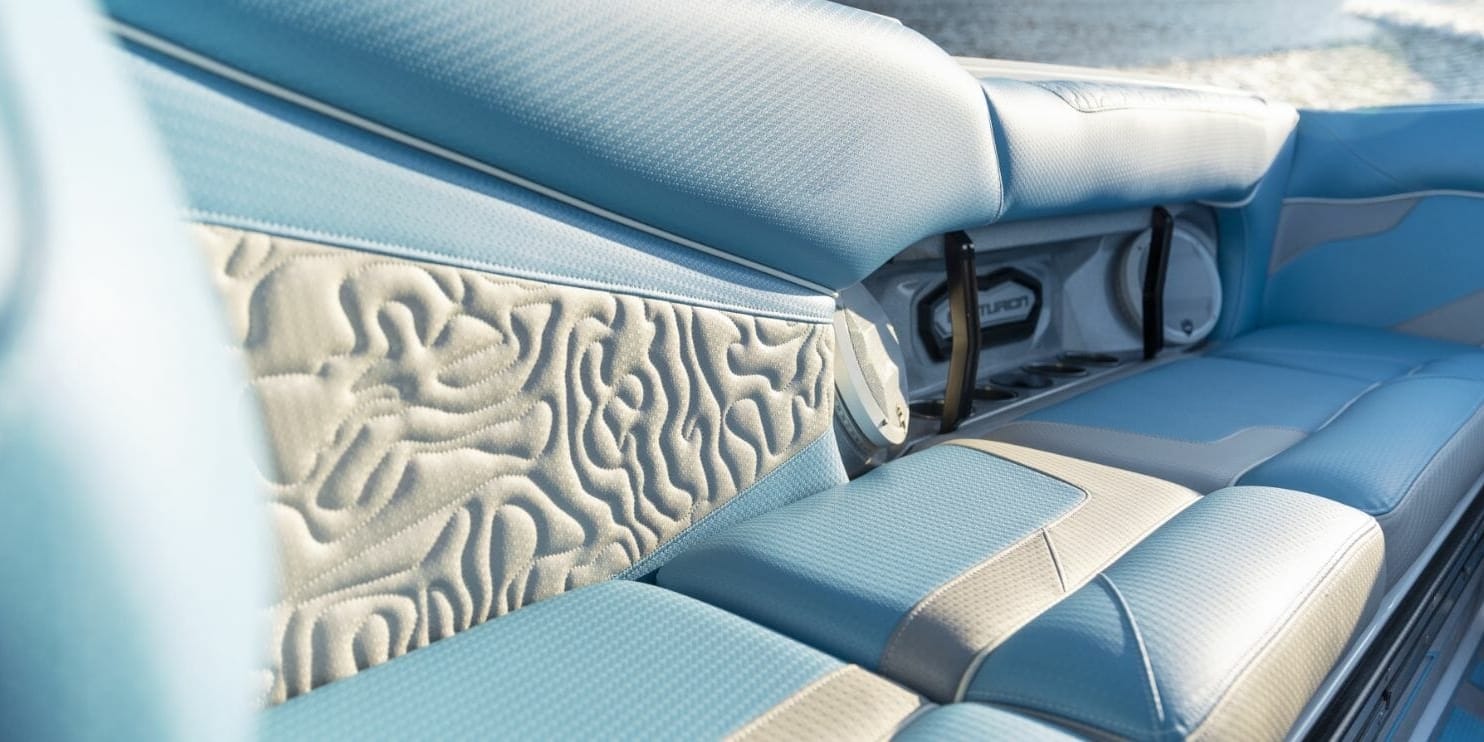 The interior of a wakesurf boat with blue leather seats.