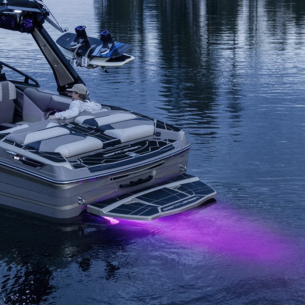A wakesurf boat with a purple light attached to it.
