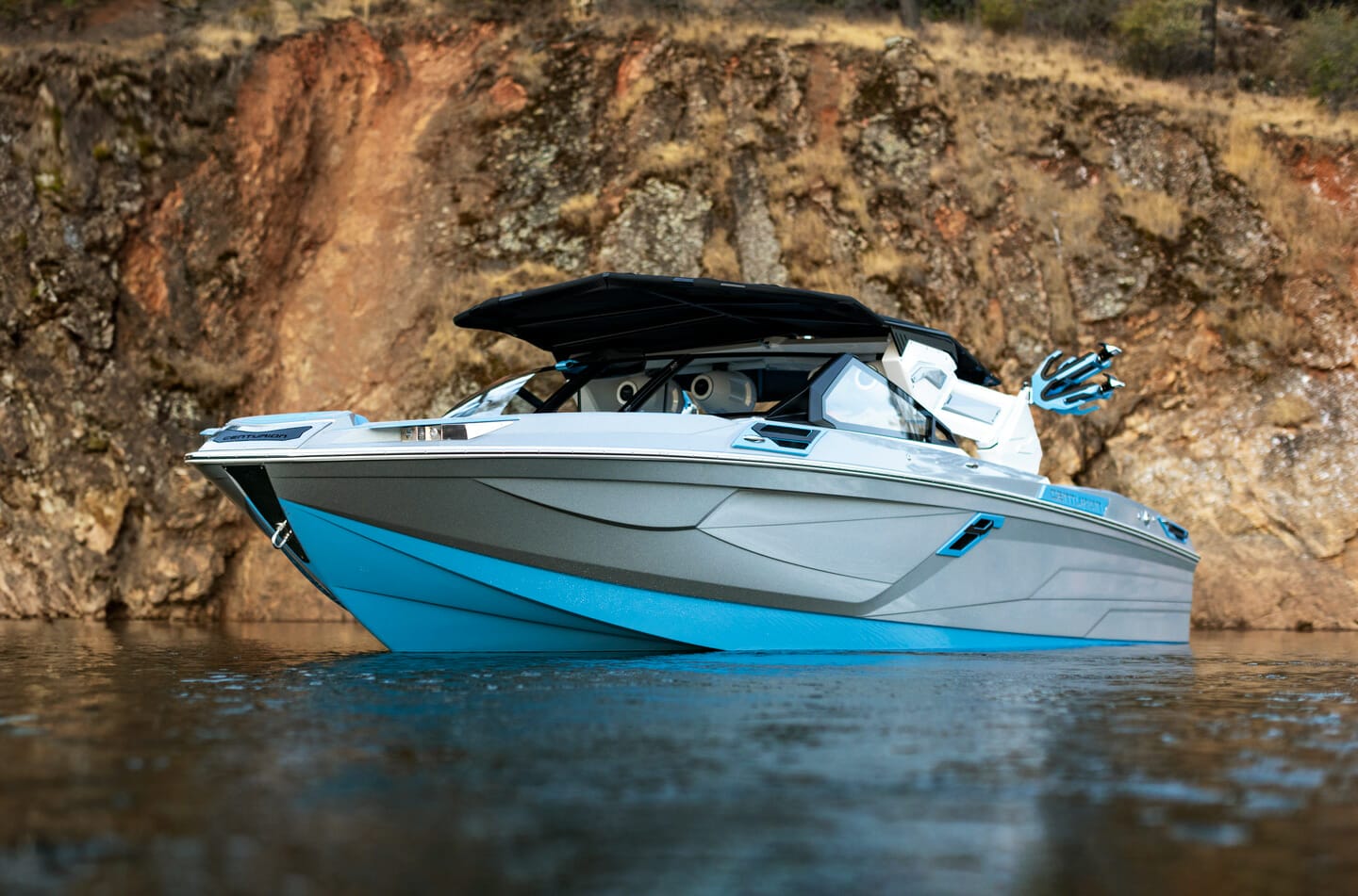 A blue and white wakesurf boat on a body of water.